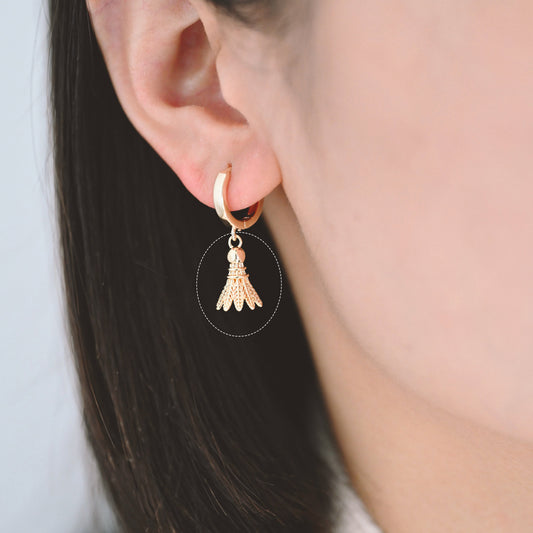 May include: Gold hoop earrings with a badminton shuttlecock charm hanging from each hoop.