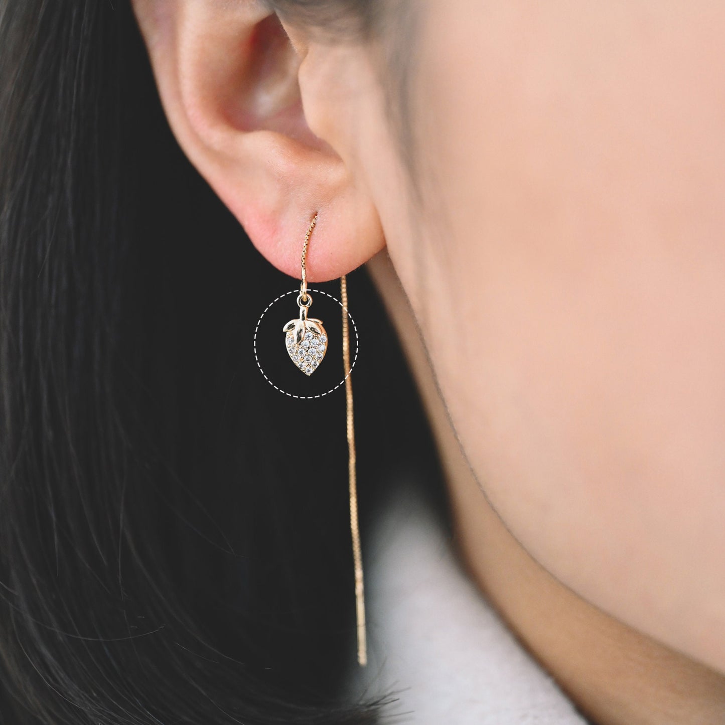 May include: A gold chain earring with a small, heart-shaped charm that is encrusted with clear rhinestones.