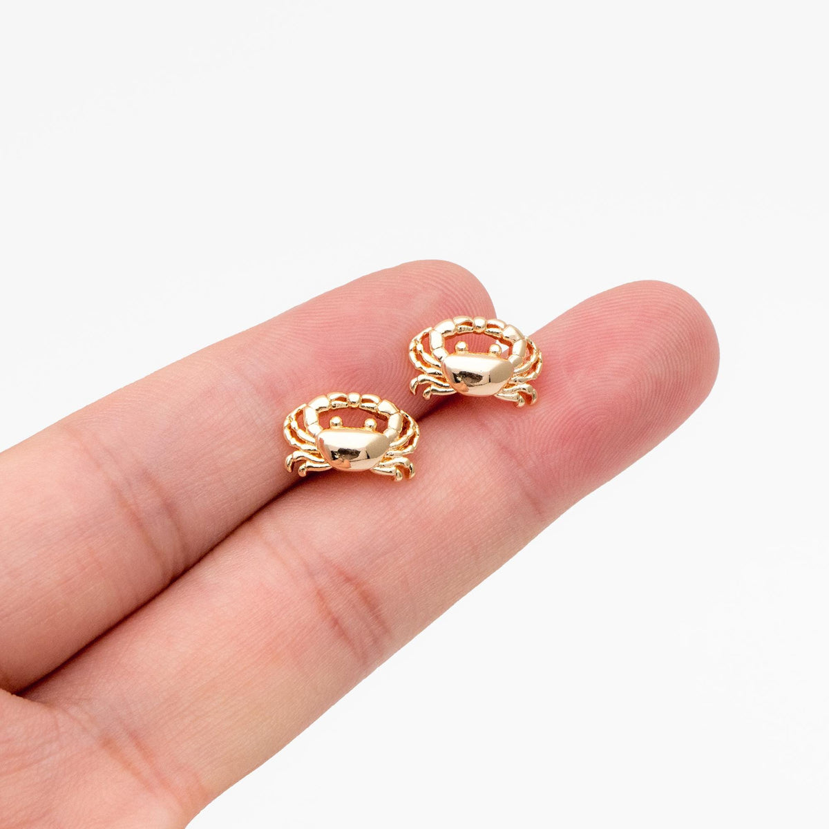 May include: A pair of gold-toned crab stud earrings. The earrings are small and delicate, and they feature a realistic crab design.