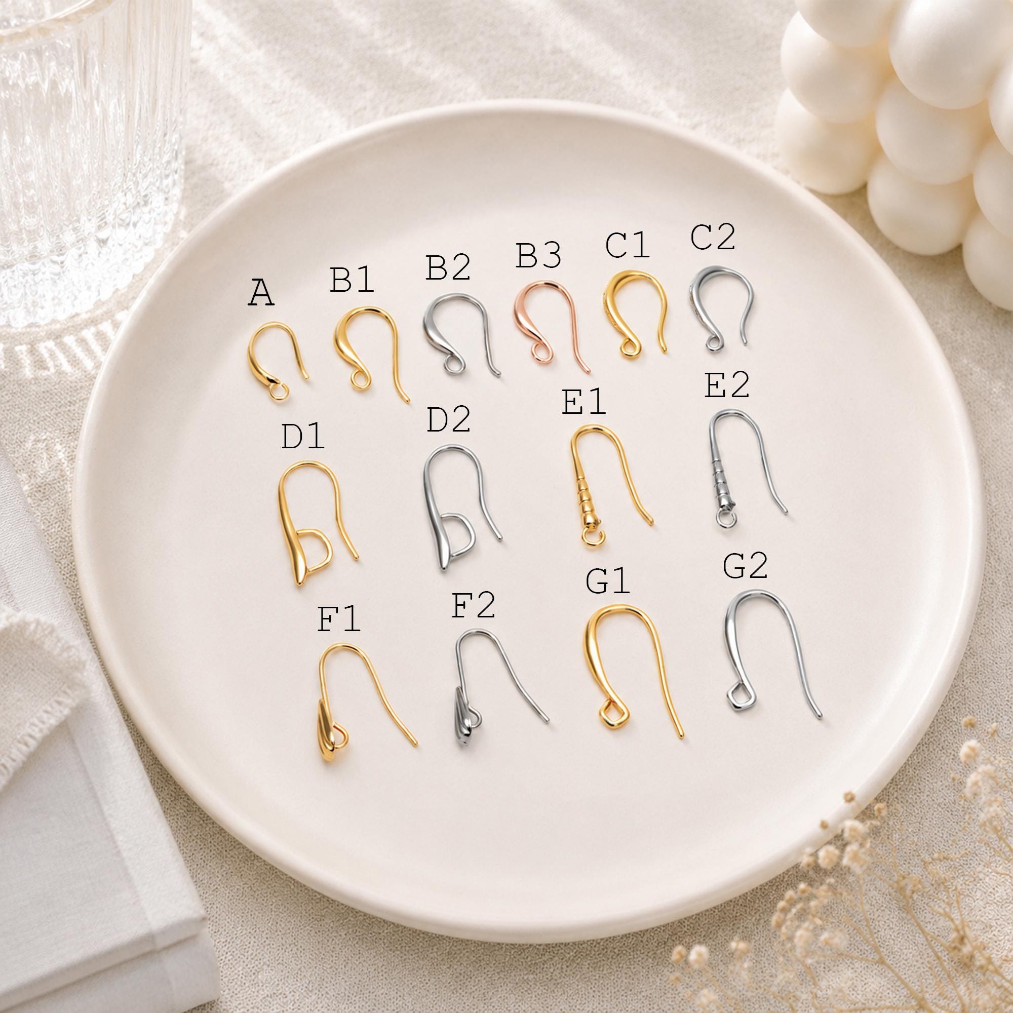 May include: A collection of metal earring hooks in various shapes and finishes, including gold, silver, and rose gold tones. Each hook is labeled with a letter and number code, such as A, B1, B2, B3, C1, C2, D1, D2, E1, E2, F1, F2, G1, and G2.